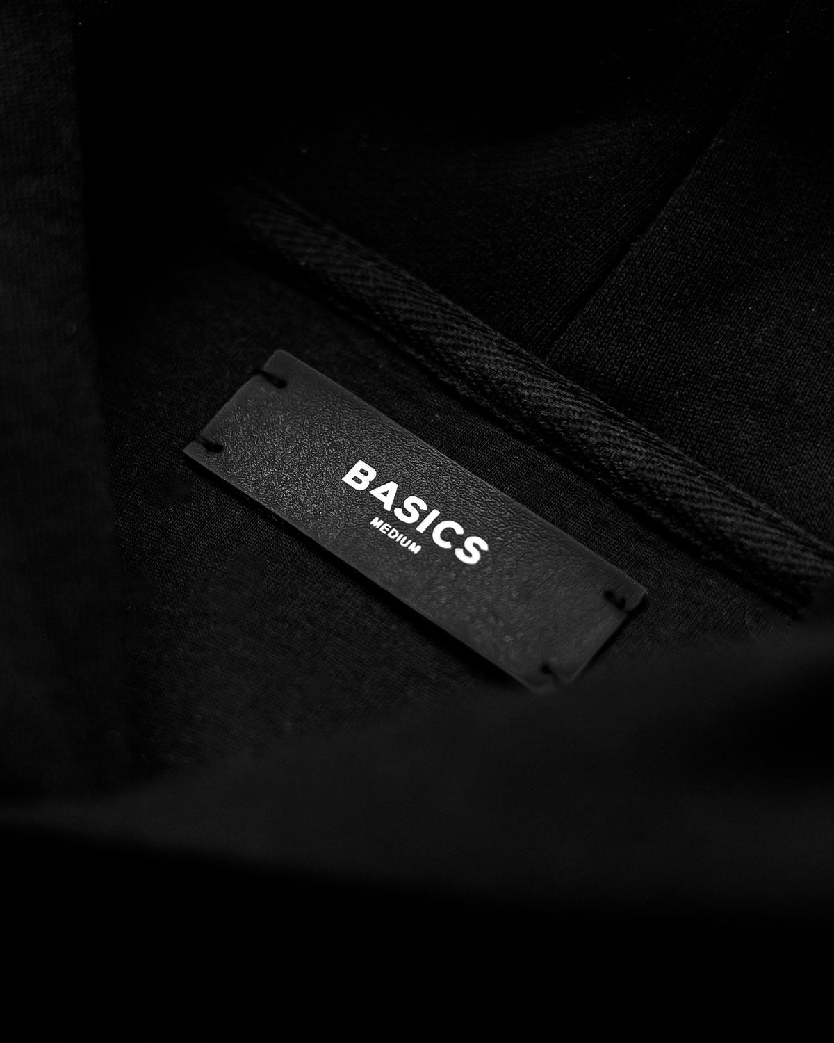 The Founders Hoodie negro, etiqueta BASICS del cuello